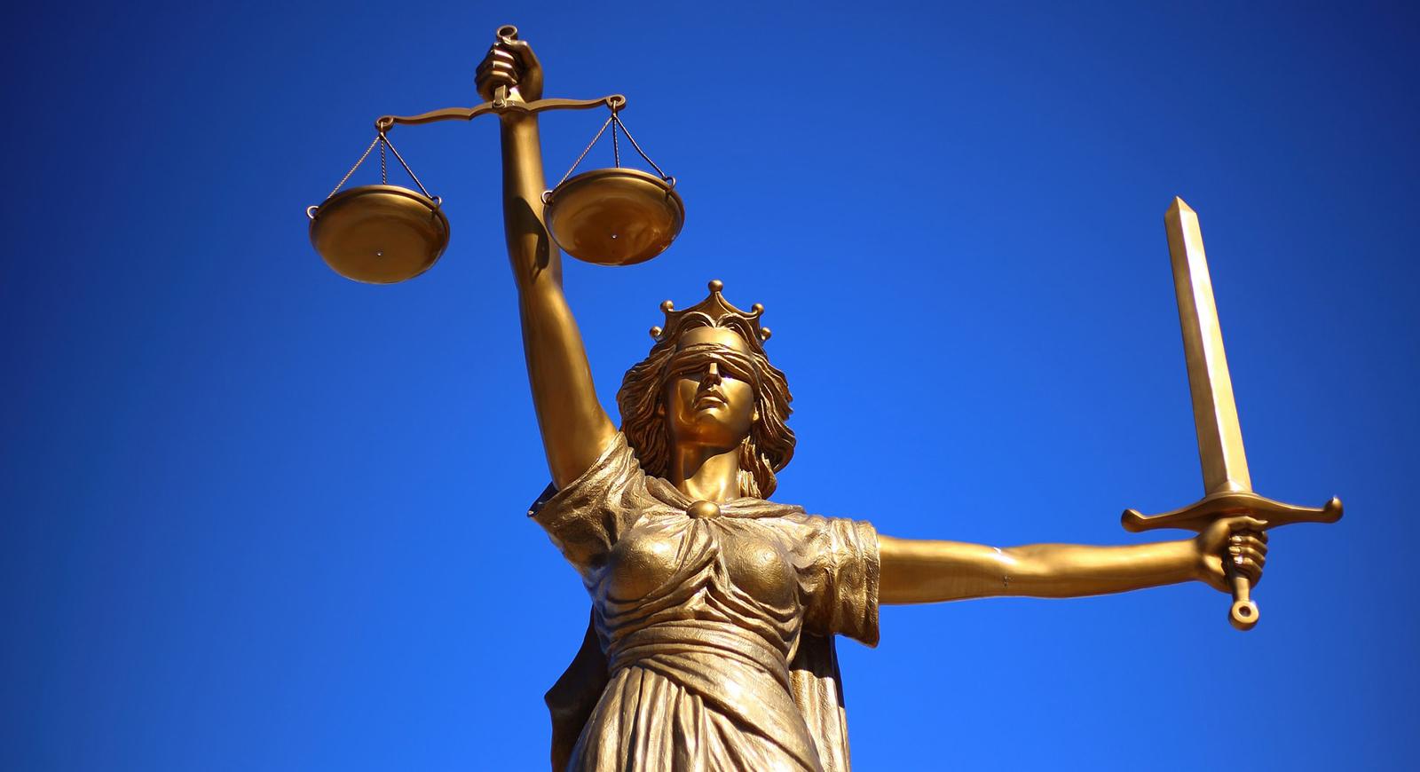 Photo of a gold statue of Justice, a blindfolded woman holding a sword and law scale. 