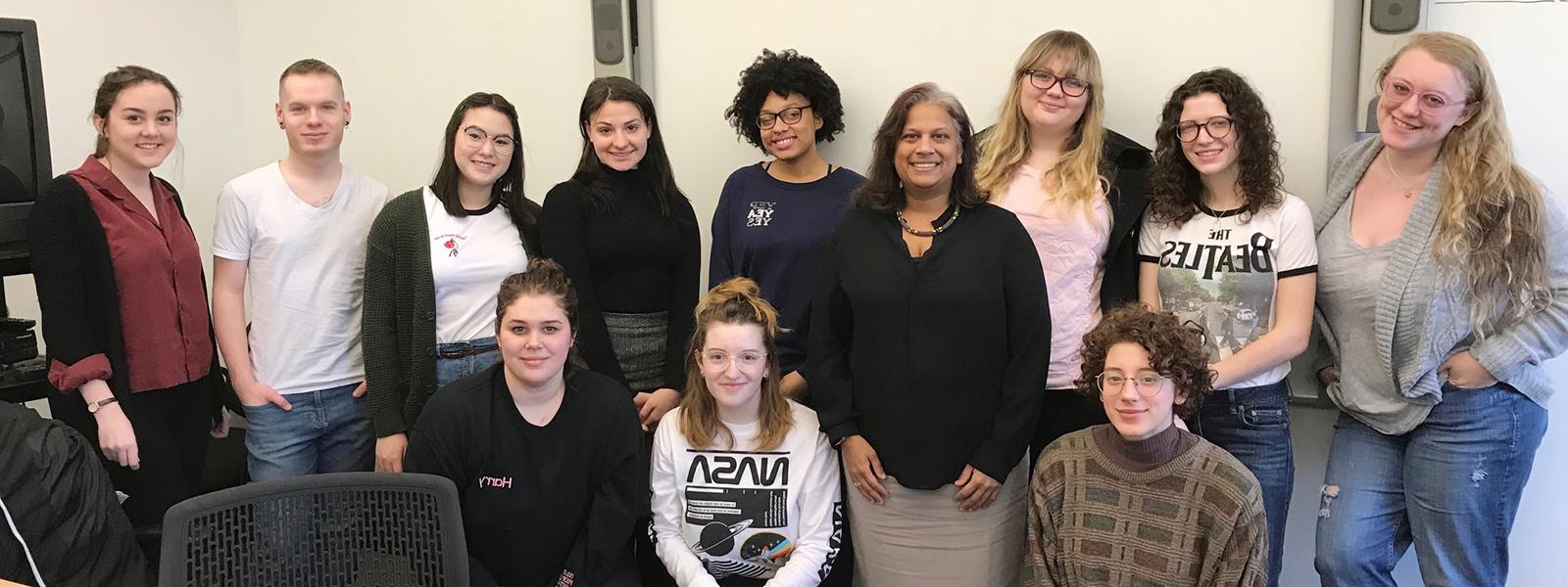 Photo of a group of students and instructor posing together at the front of a classroom