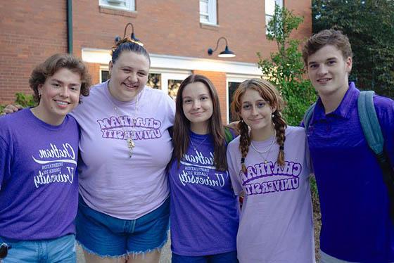 Group of five students in purple pose together and smile for a photo